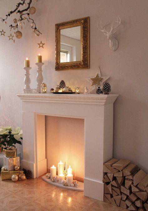 a faux fireplace with white pillar candles, neutral ornaments and stars for creating a Christmas ambience