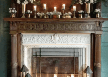 wood oak fireplace with white marble surround white candles at bottom with black lanterns and candles on mantle