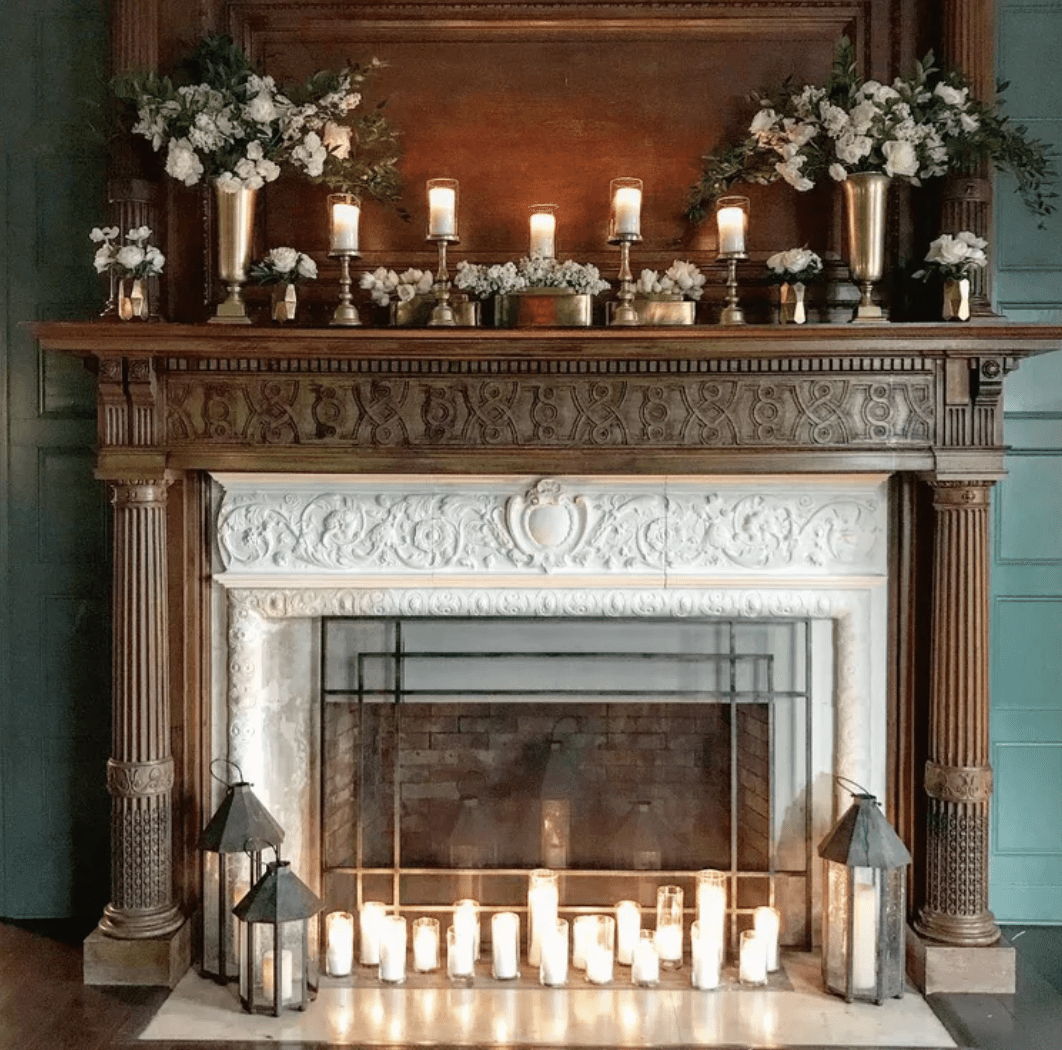 wood oak fireplace with white marble surround white candles at bottom with black lanterns and candles on mantle