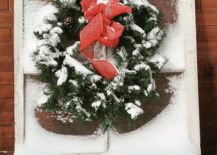 evergreen wreath with red bow hanging on snow covered window