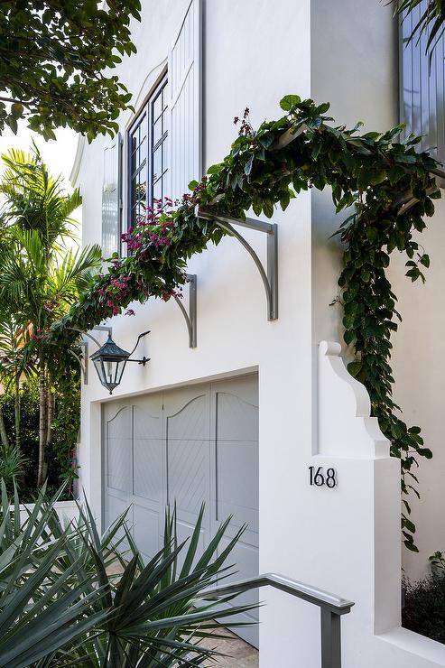 Chic garage features a gray paneled door illuminated by a carriage lantern situated under a guest apartment finished with gray shutters.