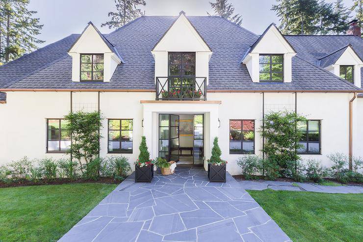Gray pavers lead to a glass and steel front door flanked by glass and steel sidelights and fixed under a Juliet balcony.