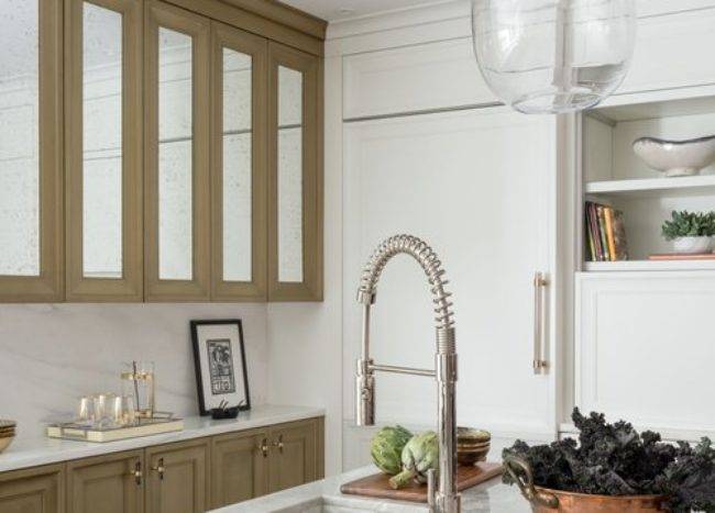 A pull-out faucet is fixed to a gray marble kitchen island countertop over a gray marble sink in a beautifully appointed kitchen.