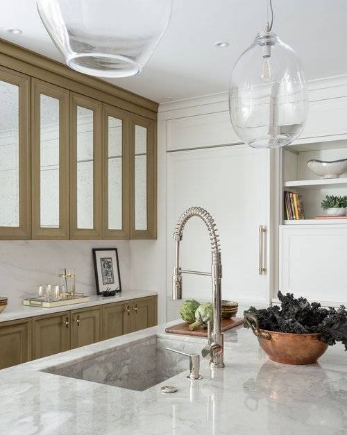 A pull-out faucet is fixed to a gray marble kitchen island countertop over a gray marble sink in a beautifully appointed kitchen.