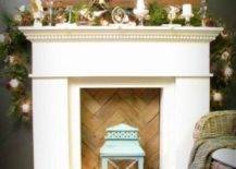 a faux fireplace with a chevron wooden screen, a crate with pinecones, candles, fir brnahces and a blue lantern