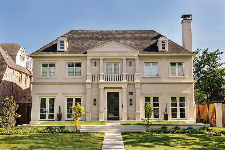 French limestone home features a balcony over a black front door.