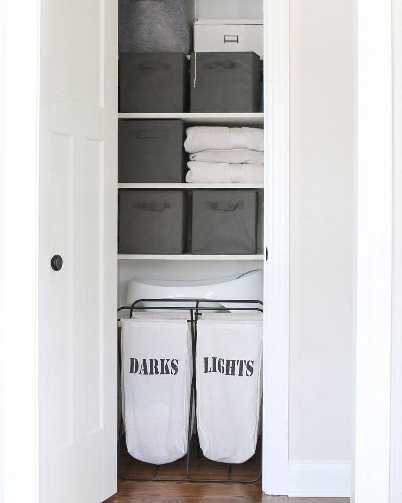 inside of bathroom linen closet with baskets and laundry separated hamper