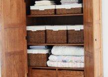 open brown cupboard full of towels and wicker baskets