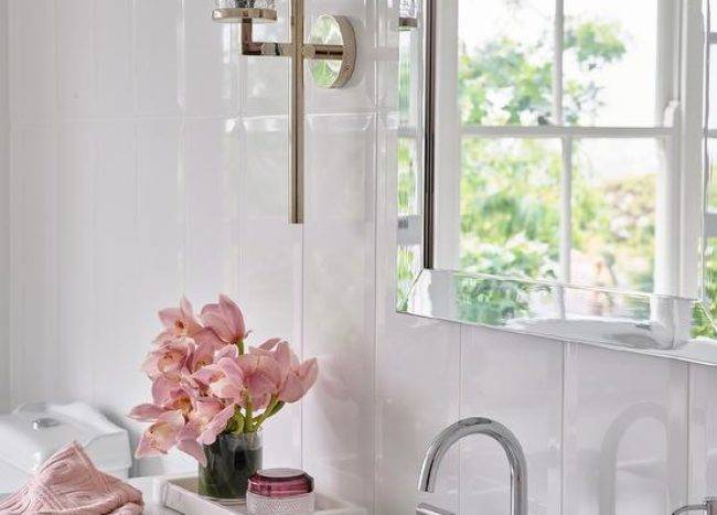Bathroom features a chrome beveled mirror on a glossy white vertical plank wall over a marble tray on a marble look countertop.
