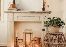 white fireplace mantle with lit candles in front mirror wicker plant stand