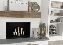 modern boho farmhouse fireplace with candles inside white let's stay home sign on mantle and floor pouf