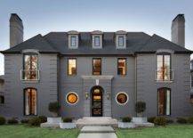 Stunning home features a gray stone exterior accented with glass and iron windows with modern Juliet balconies.