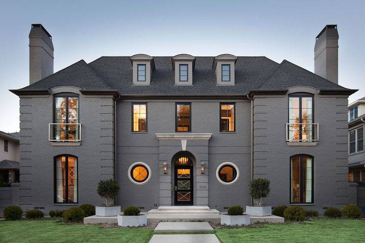 Stunning home features a gray stone exterior accented with glass and iron windows with modern Juliet balconies.