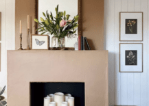 modern stucco fireplace with white pillar candles inside vase with flowers on mantle mirror and butterfly picture