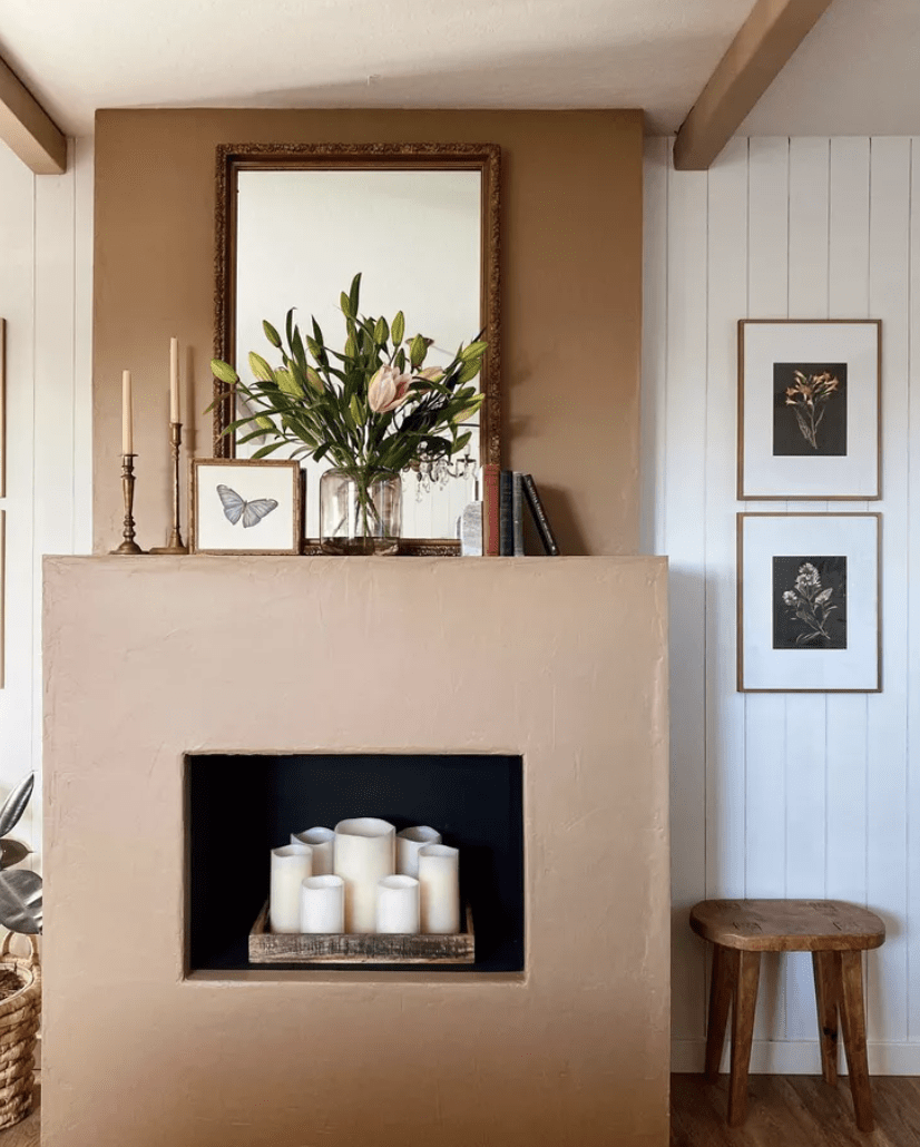 modern stucco fireplace with white pillar candles inside vase with flowers on mantle mirror and butterfly picture