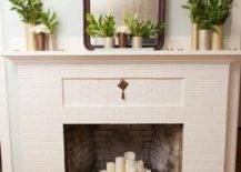 a non-working fireplace of brick, with a metal stand for firewood and pillar candles on it