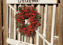 red berry wreath on old garden gate that says welcome
