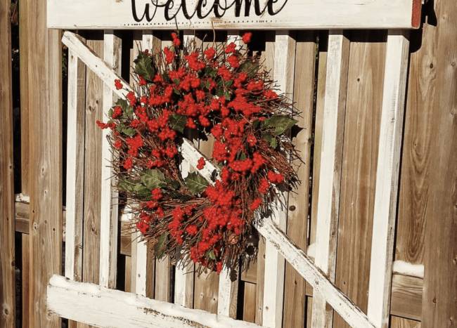 red berry wreath on old garden gate that says welcome