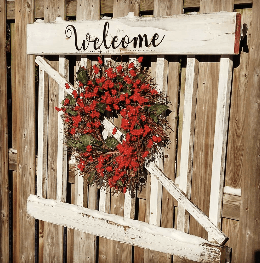 red berry wreath on old garden gate that says welcome