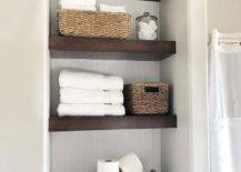 open shelving closet in bathroom with wood shelves beadboard backing baskets folded white towels toilet paper