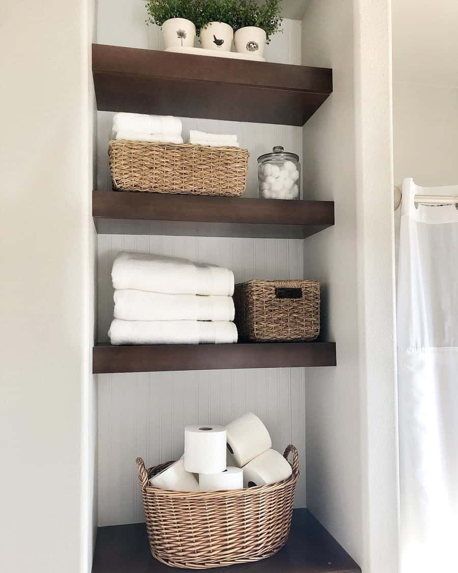 open shelving closet in bathroom with wood shelves beadboard backing baskets folded white towels toilet paper