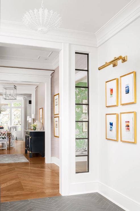 A brass picture light is mounted to a white wall over gold gallery frames.