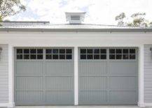 Side-by-side gray plank garage doors are lit by nickel lanterns.