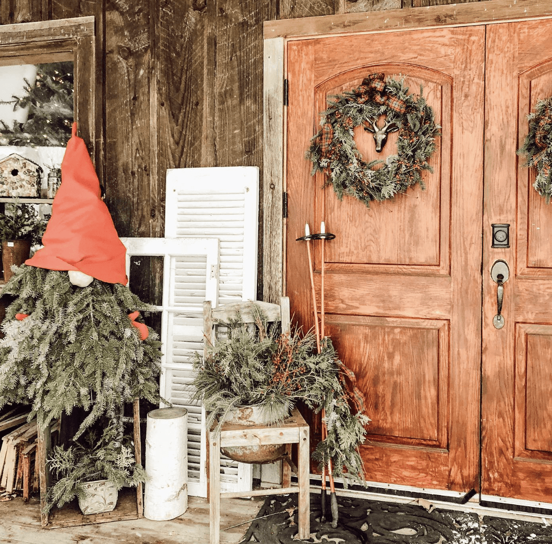 evergreen holiday wreath and decorations on front porch with wooden double doors