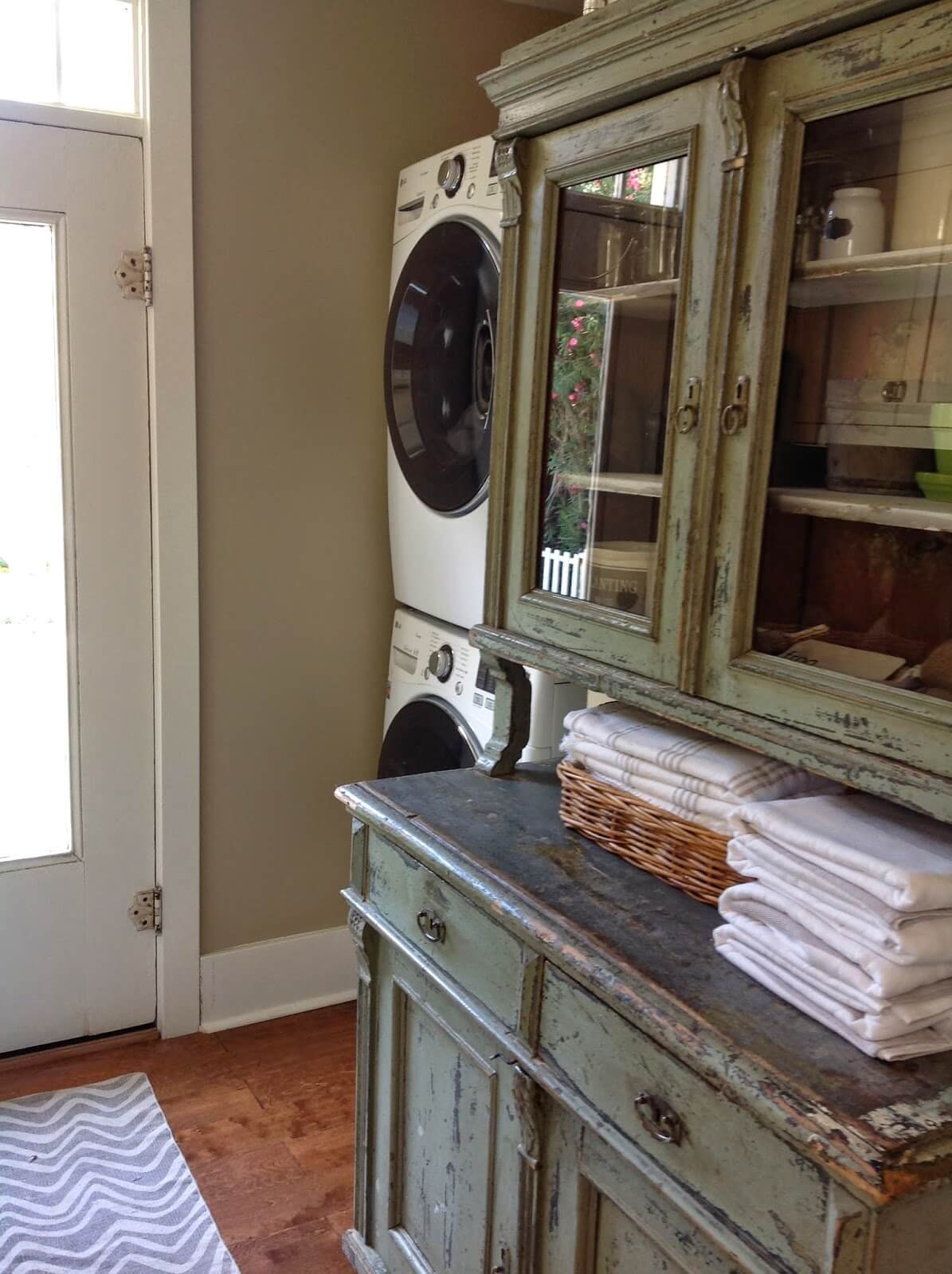 repurposed hutch in laundry room stacked washer and dryer folded towels on hutch