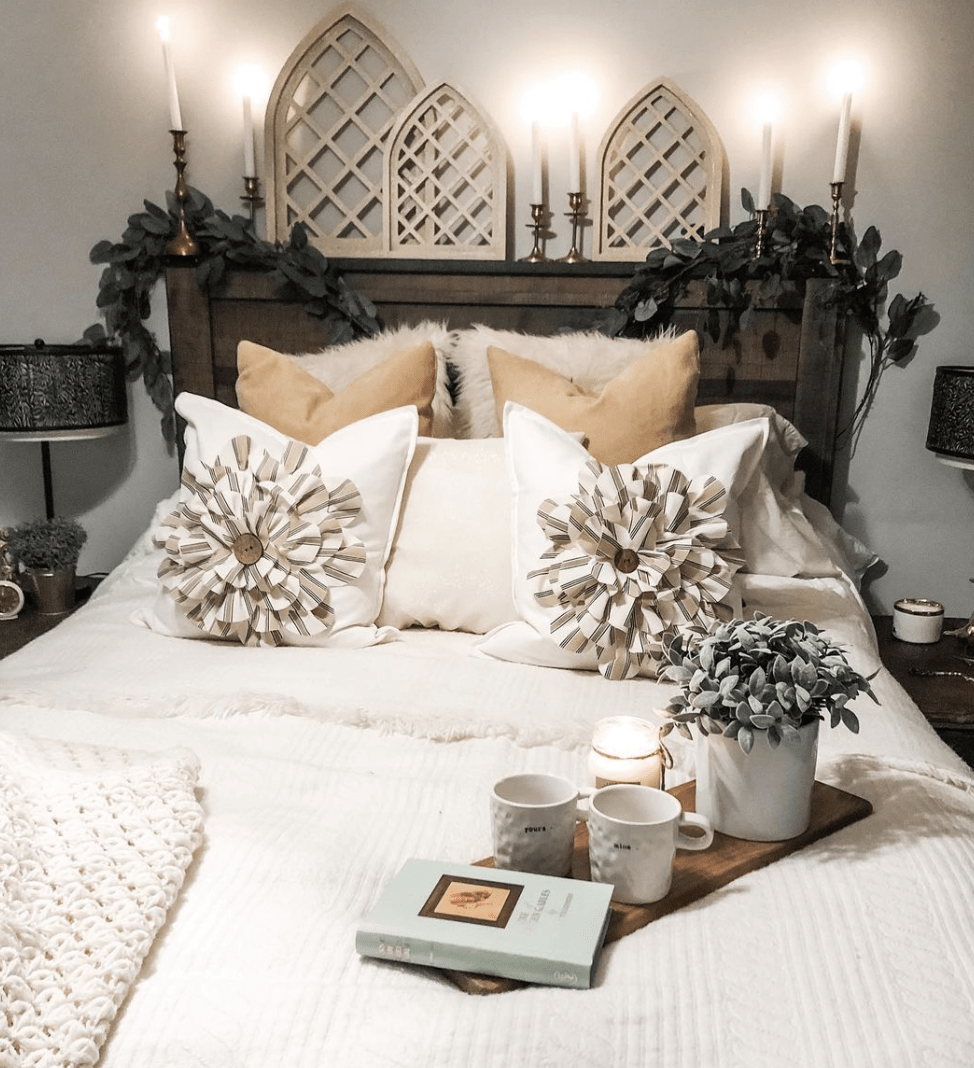 country chic cottage style bedroom master primary bed with white covers flower pillows bed tray wood lattice architecture candles brass candlesticks greenery