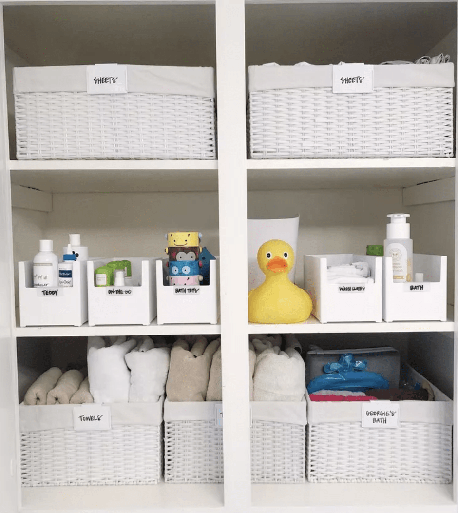 white bathroom closet organized with bins plastic totes weaved baskets with labels
