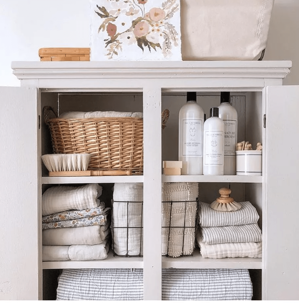 Open closet shelf in bathroom with towels neutral and cleaning accessories shampoos and lotions