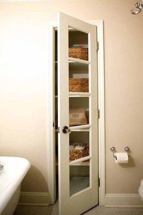 Bathroom features small linen cabinet with glass door over vintage penny tiled floor.