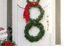 snowman wreath made out of evergreen hanging on white door
