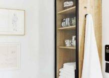 storage cabinet with towel hanging on the side walnut light wood white walls bathroom