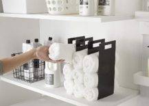 interlocking towel organizer with white towels on laundry room shelf next to shampoos and soap bottles