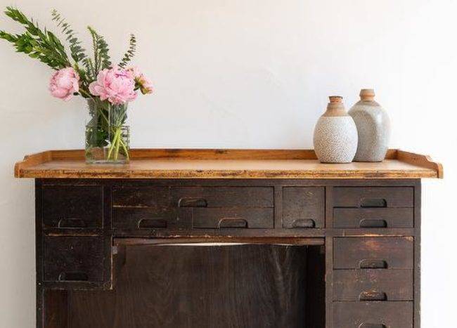 Workspace features vintage wooden desk with drawers.