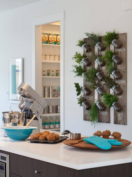 A Studio N2 Herb Garden hangs on the wall behind the modern coffee colored kitchen island with polished nickel hardware and white countertop.