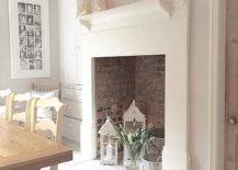 a large non-working fireplace with bricks inside, candle lanterns, flwoers and whitewashed baskets is chic