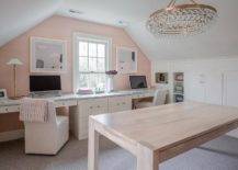Spacious white and pink home office with pink walls features white built in desks with white slipper chairs and a brown lacquer table lit by a Robert Abbey bling chandelier.
