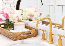 A round sink is fitted to a honed white marble washstand countertop finished with a brushed gold faucet.
