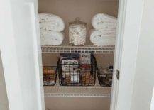 wire shelving in bathroom closet with folded towels apothecary jars wire baskets with toilet paper