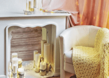white fireplace s، with pillar candles and ،le light white chair with yellow afgan