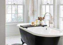 Black clawfoot tub with a black tray and a chrome floor mount tub filler in a cottage master bathroom boasting white hexagon floor tiles.