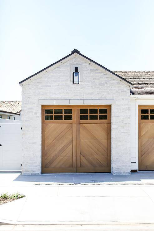 A white brick garage is accented with wooden chevron garage doors.