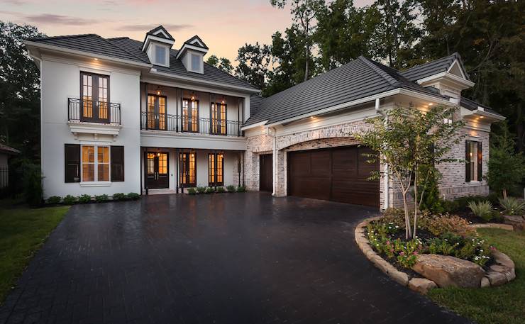 Gorgeous home exterior features sleek white exterior accented with gray shingled roof over black French doors and Juliet balconies as well as an attached 3 car garage.