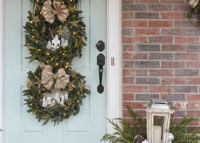trio of three christmas wreaths hanging on light blue door with lights