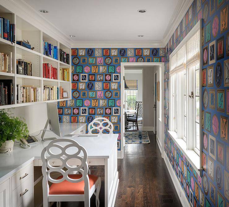 Beautifully designed home office is covered in Hunt Slonem Bunny Wall Wallpaper. Windows dressed in white roman shades face a built-in desk seating two Bungalow 5 Loop Chairs and flanked by white built-in cabinets locate under modular bookcases.