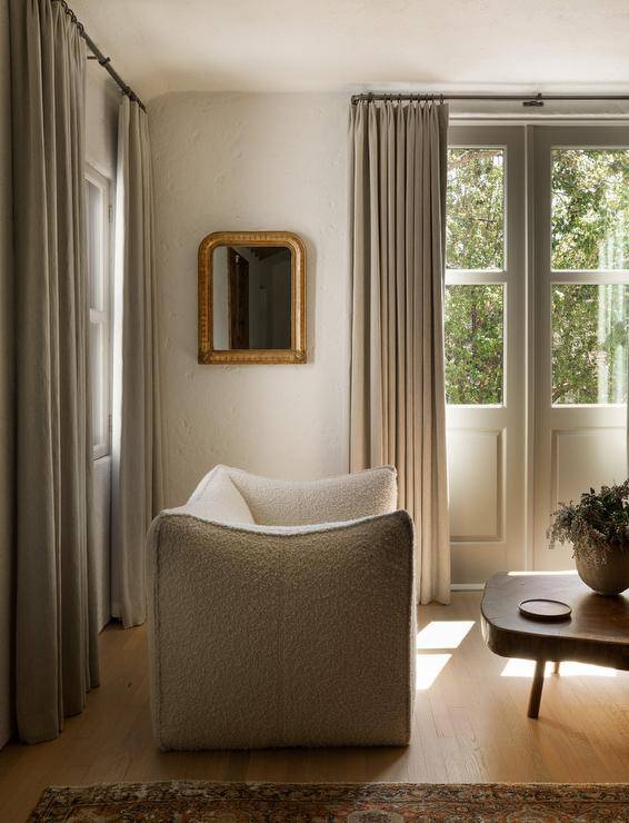 Living room features a white boucle chair with live edge coffee table and tan curtains.