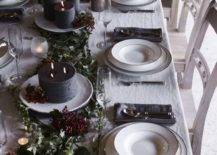 a chic dark tone winter tablescape with dark candles, greenery, berries, grey napkins and white porcelain